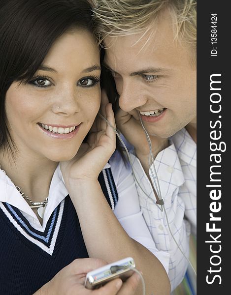 Young couple sharing headphones listening to MP3 player, portrait, close up
