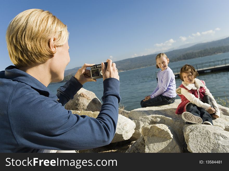 Mother taking picture of daughters at the lake