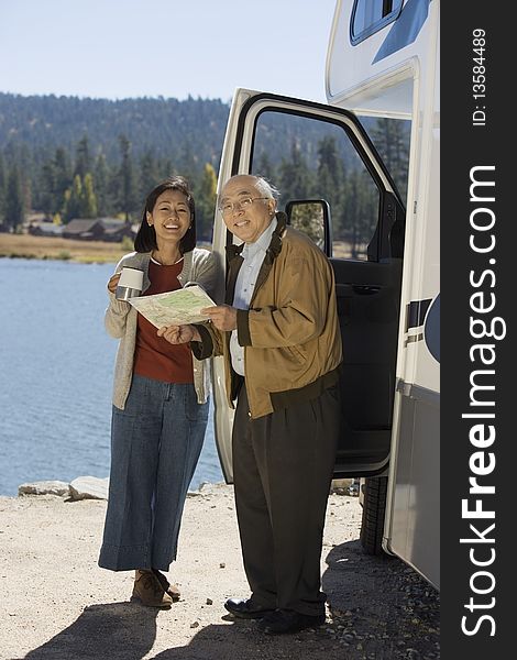 Senior couple looking at map outside RV at lake