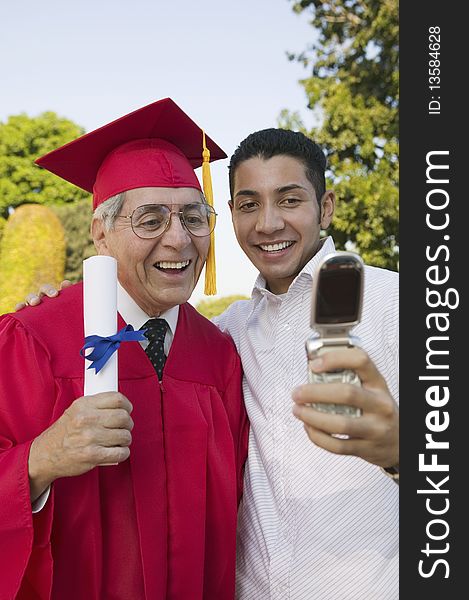 Senior Graduate and son taking picture with cell phone outside