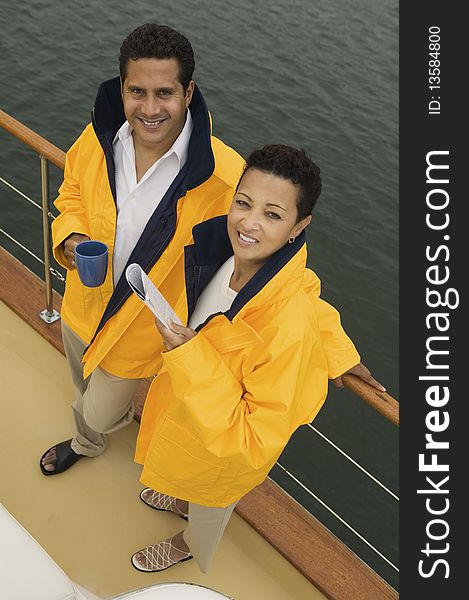 Couple wearing yellow anoraks on yacht, (portrait), (elevated view)