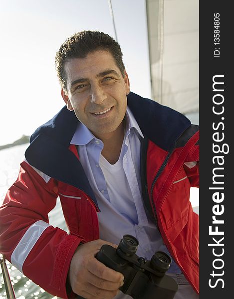Man holding binoculars on yacht, (portrait)