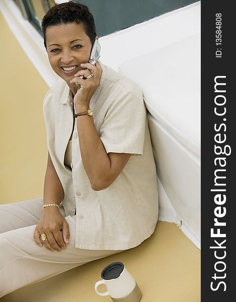 Woman sitting on yacht, talking on mobile phone, (portrait), (elevated view)