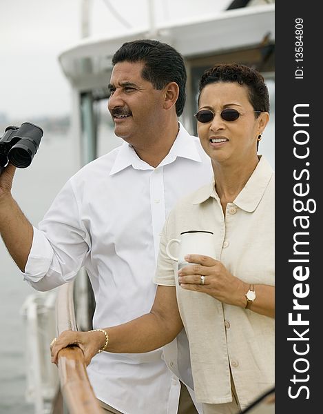 Middle aged Couple on yacht, man holding binoculars