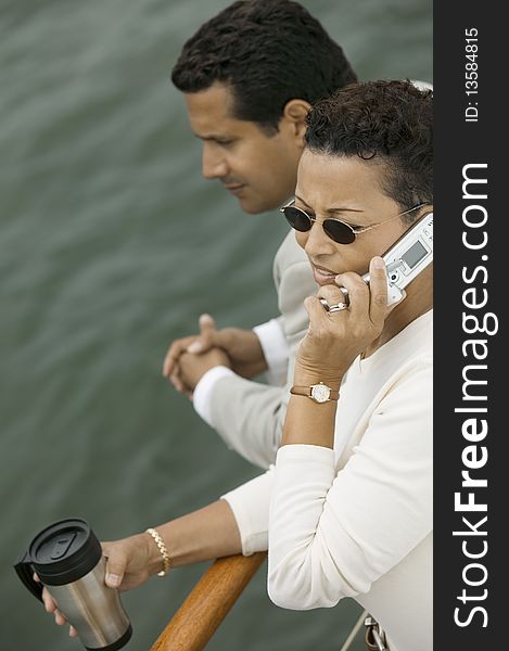 Couple relaxing on yacht, woman talking on mobile phone, (elevated view)