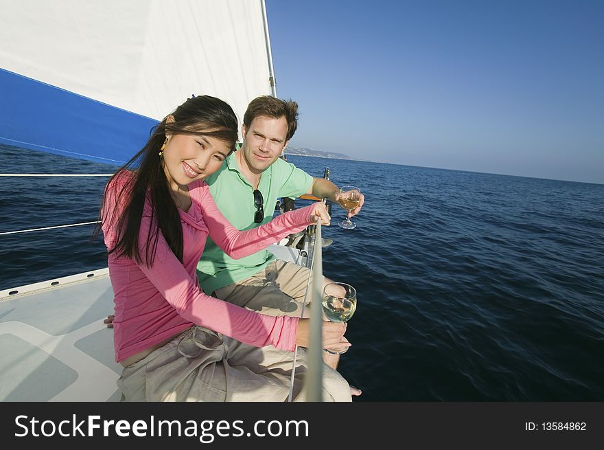 Couple dinking white wine on sailboat, (portrait)