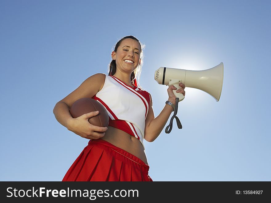 Cheerleader Holding Football and Megaphone, low angle view, portrait, (portrait), (low angle view)