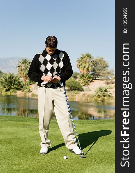 Golfer taking notes on golf course