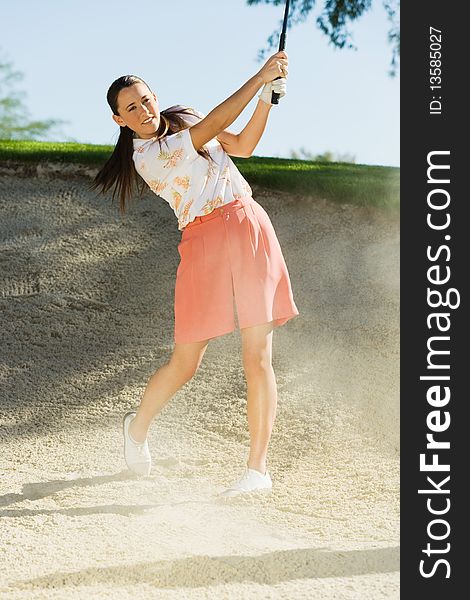 Female golfer hitting ball from sand trap