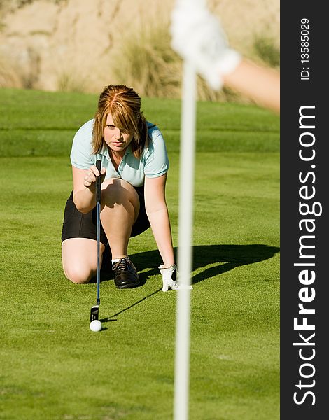 Female golfer putting while crouching on green