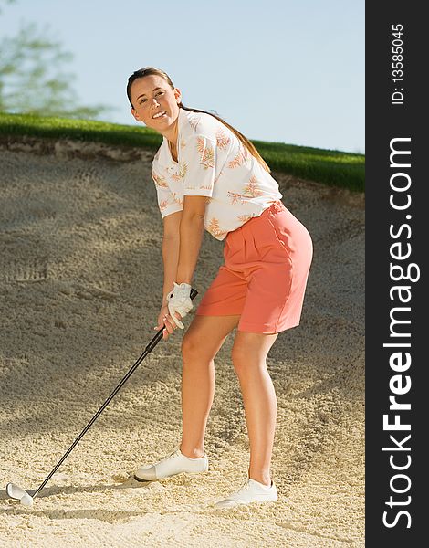 Female golfer hitting ball from sand trap