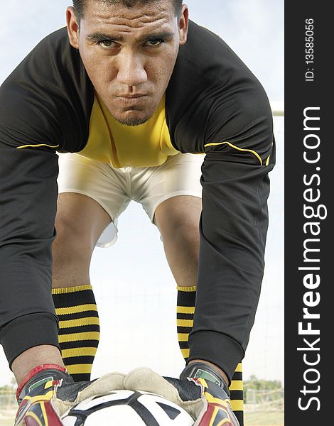 Goalkeeper bending down with ball, portrait