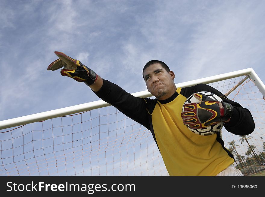 Goalkeeper pointing and holding ball, portrait