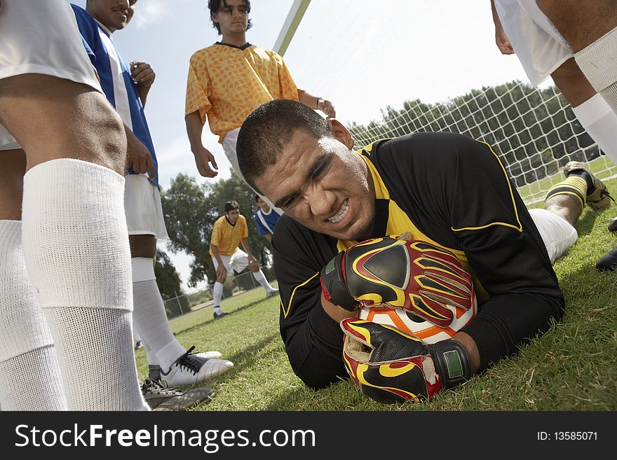 Goalkeeper on ground holding soccer ball