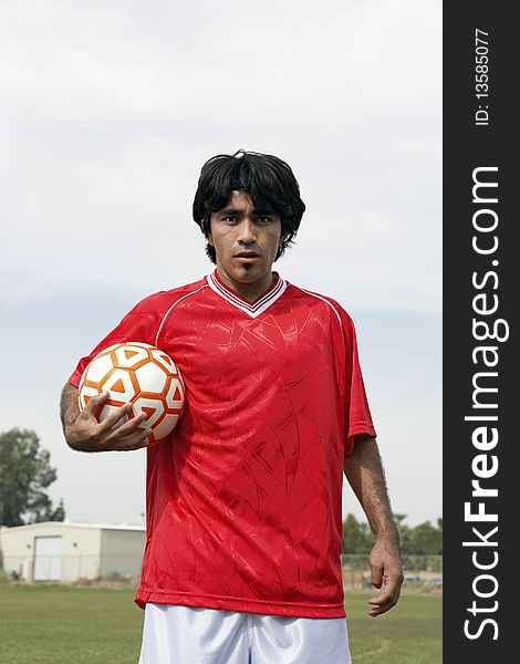 Soccer player holding ball, portrait