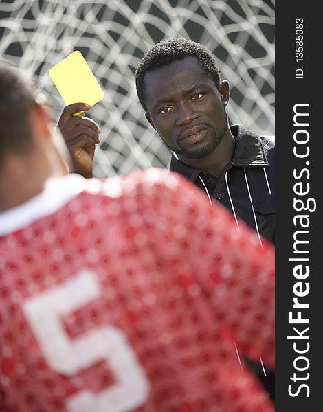 Soccer referee holding out yellow card, portrait