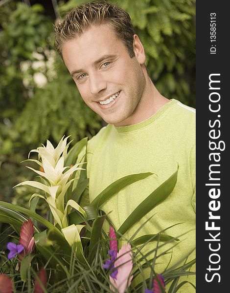 Young man holding exotic potted plant, (portrait)