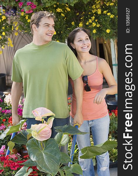 Young couple with wheelbarrow with plants in garden