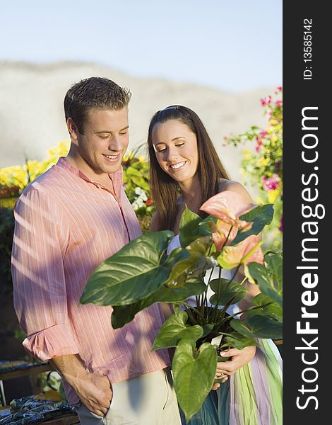 Young couple choosing potted flowers in garden centre