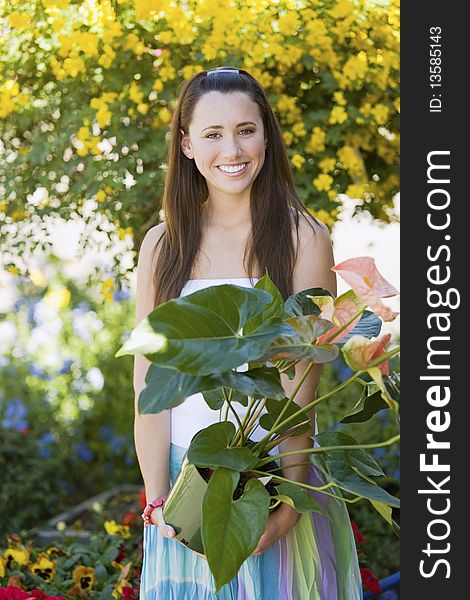 Young woman holding potted plant in garden centre, (portrait)