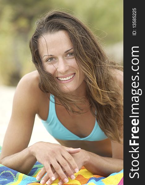 Smiling Young Woman lying down on Beach towel