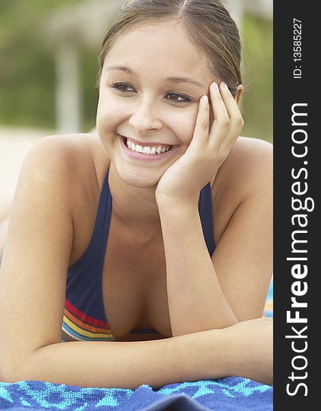 Happy Young Woman lying down on Beach towel