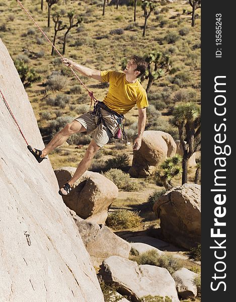 Caucasian Climber Tugging on Rope on Cliff