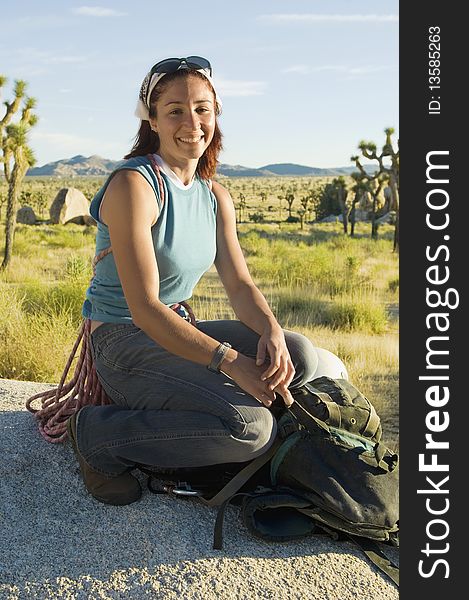 Female Climber crouching on Boulder with Gear. Female Climber crouching on Boulder with Gear