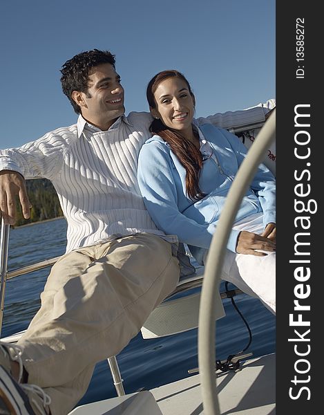 Young couple sitting at steering wheel on sailboat. Young couple sitting at steering wheel on sailboat