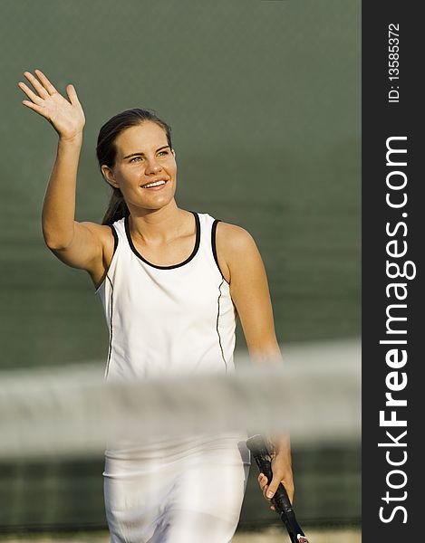 Tennis Player standing near net, arm raised and Waving