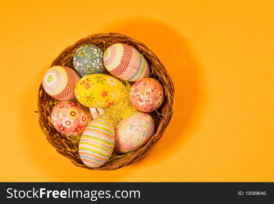 Decorated easter eggs in a basket and orange background