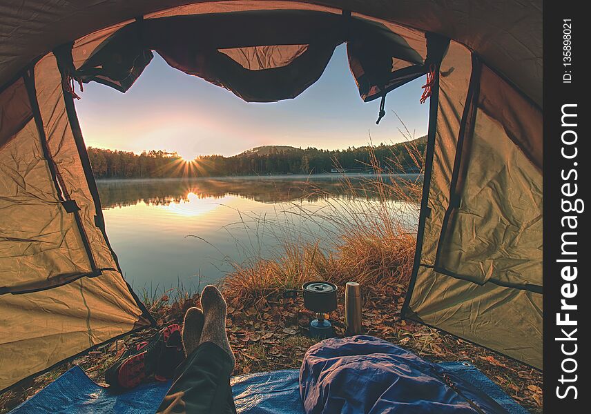 Couple legs rest in tent at lake. Hiker enjoy view outsid and e free hike vacation
