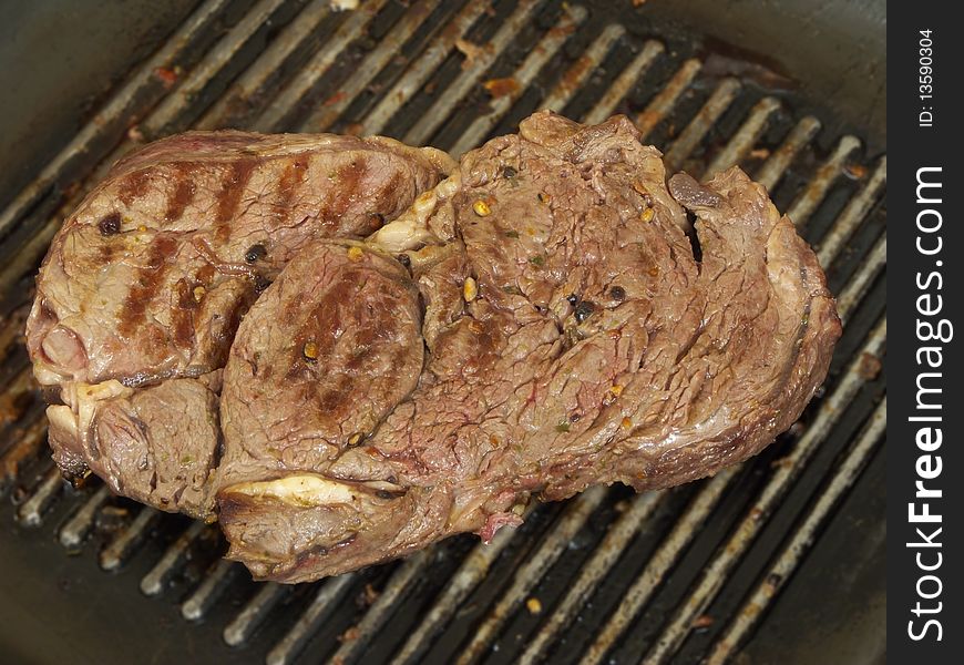 A large juicy antrecote steak on a pan, flavoured with onion, garlic, olive oil and black pepper. Bon appetite
