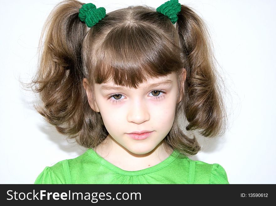 Portrait of the beautiful girl with green eyes in a green dress with two tails. Portrait of the beautiful girl with green eyes in a green dress with two tails