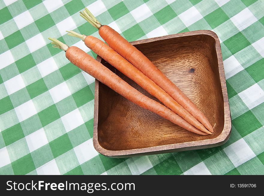 Bowl of fresh carrots on a bright green table cloth.