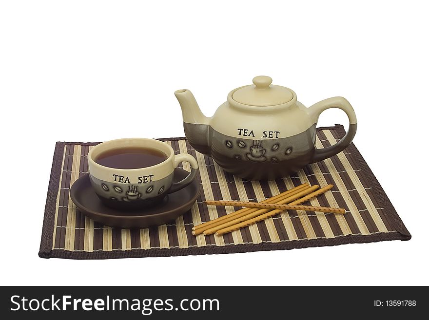 Ceramic cup and teapot on a napkin from a bamboo. Ceramic cup and teapot on a napkin from a bamboo