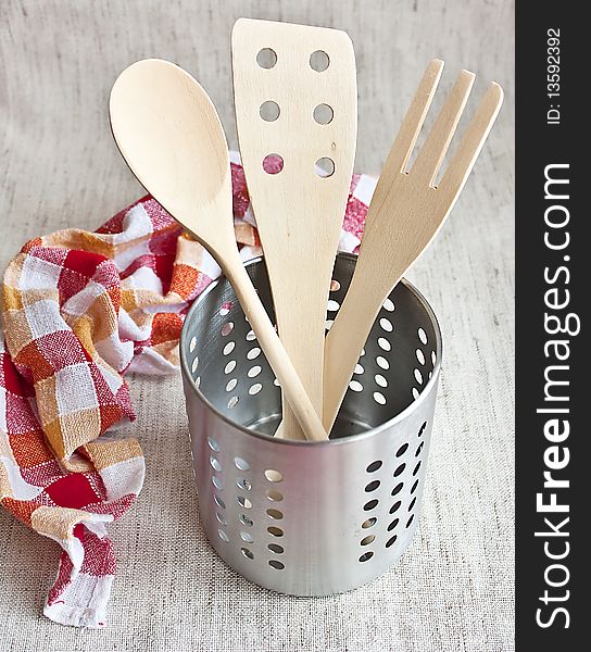 Wooden spoons in a metal jar with kitchen towel on fabric background. Wooden spoons in a metal jar with kitchen towel on fabric background