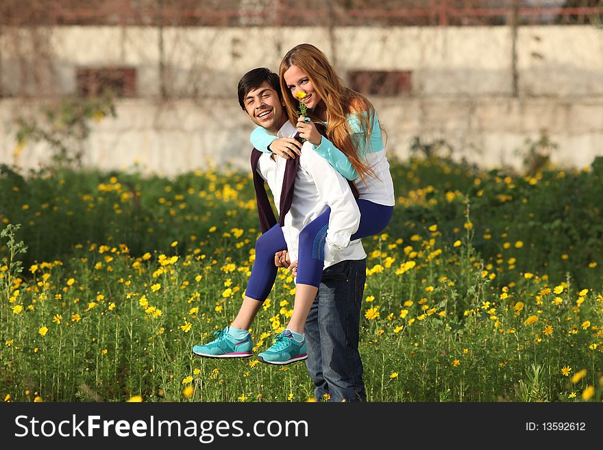 Young couple piggy-backing in meadow
