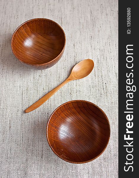 Wooden bowls and wooden spoon on fabric background