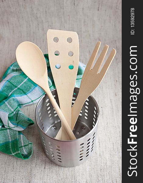 Wooden spoons in a metal jar with kitchen towel on fabric background. Wooden spoons in a metal jar with kitchen towel on fabric background