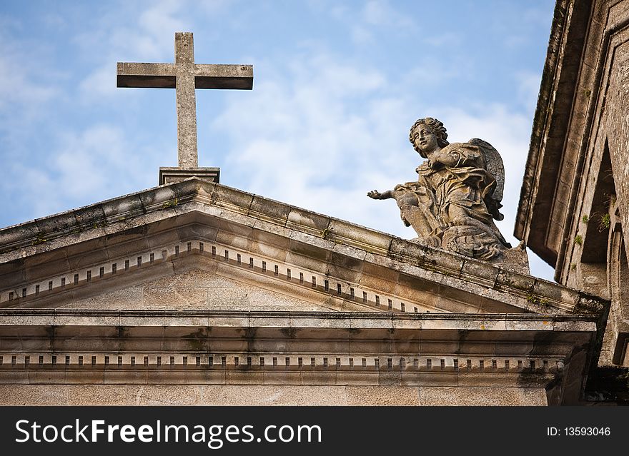 Roof of the old Christ the Rock church with a cross and an angel on a background of blue sky