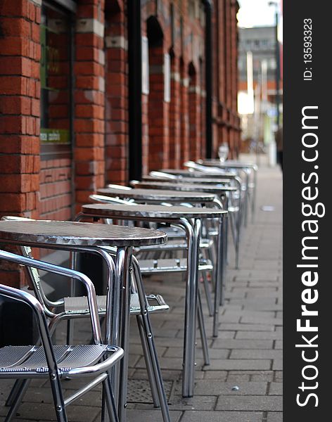 Tables and chairs on the street in front of a restaurant