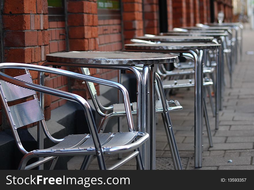 Tables and chairs on the street in front of a restaurant