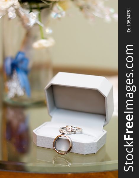 Wedding rings still life with floral bouquet in a vase in the background. Wedding rings still life with floral bouquet in a vase in the background.