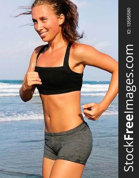 Photo of sports girl runs along the beach. Photo of sports girl runs along the beach