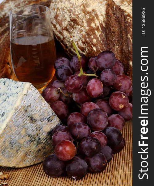 Close up with moldy cheese, glass, bread and red grapes isolated. Close up with moldy cheese, glass, bread and red grapes isolated