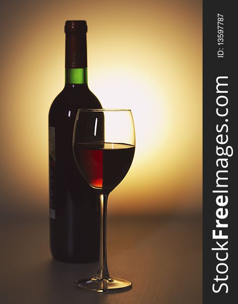 Bottle and a glass of red wine on an abstract background