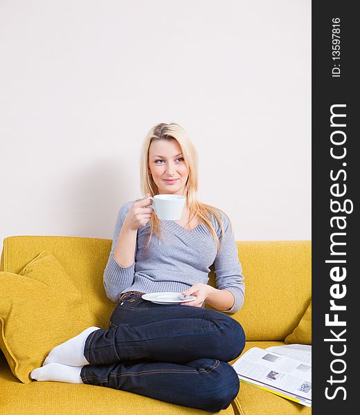 Woman sitting on sofa, reading magazine and having coffee. Woman sitting on sofa, reading magazine and having coffee