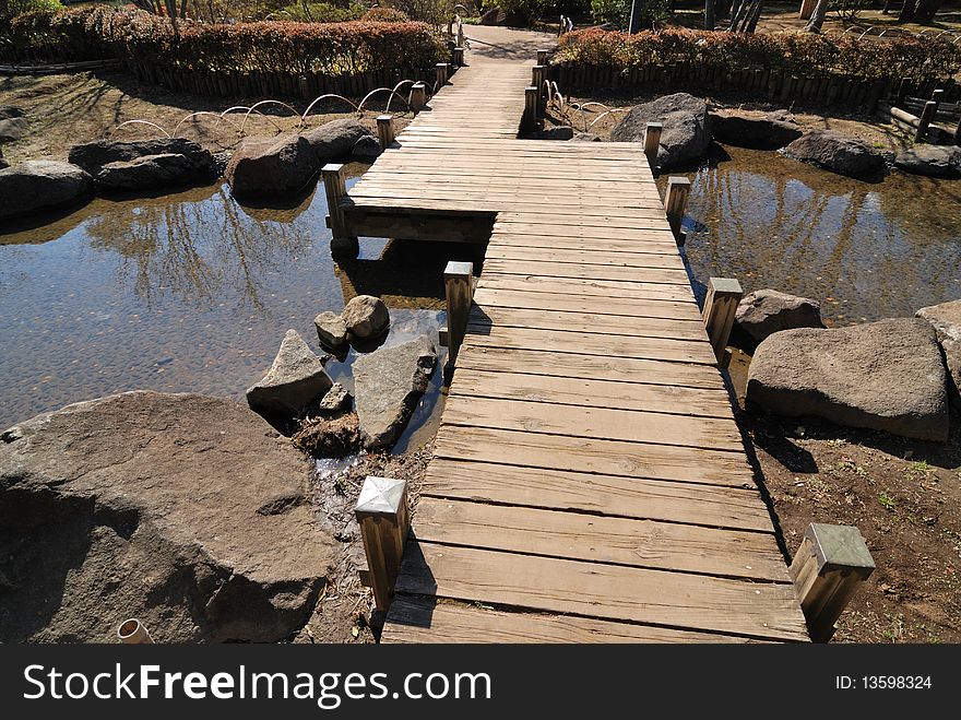 Scenic wooden bridge in Japanese garden by bright sunny day