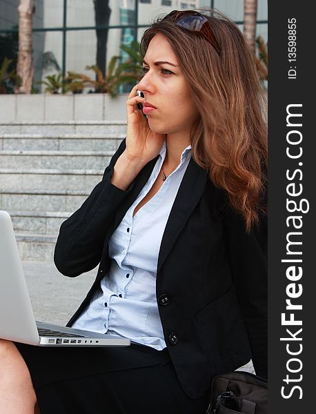 Business woman sitting on stairs with laptop and talking on the phone. Business woman sitting on stairs with laptop and talking on the phone